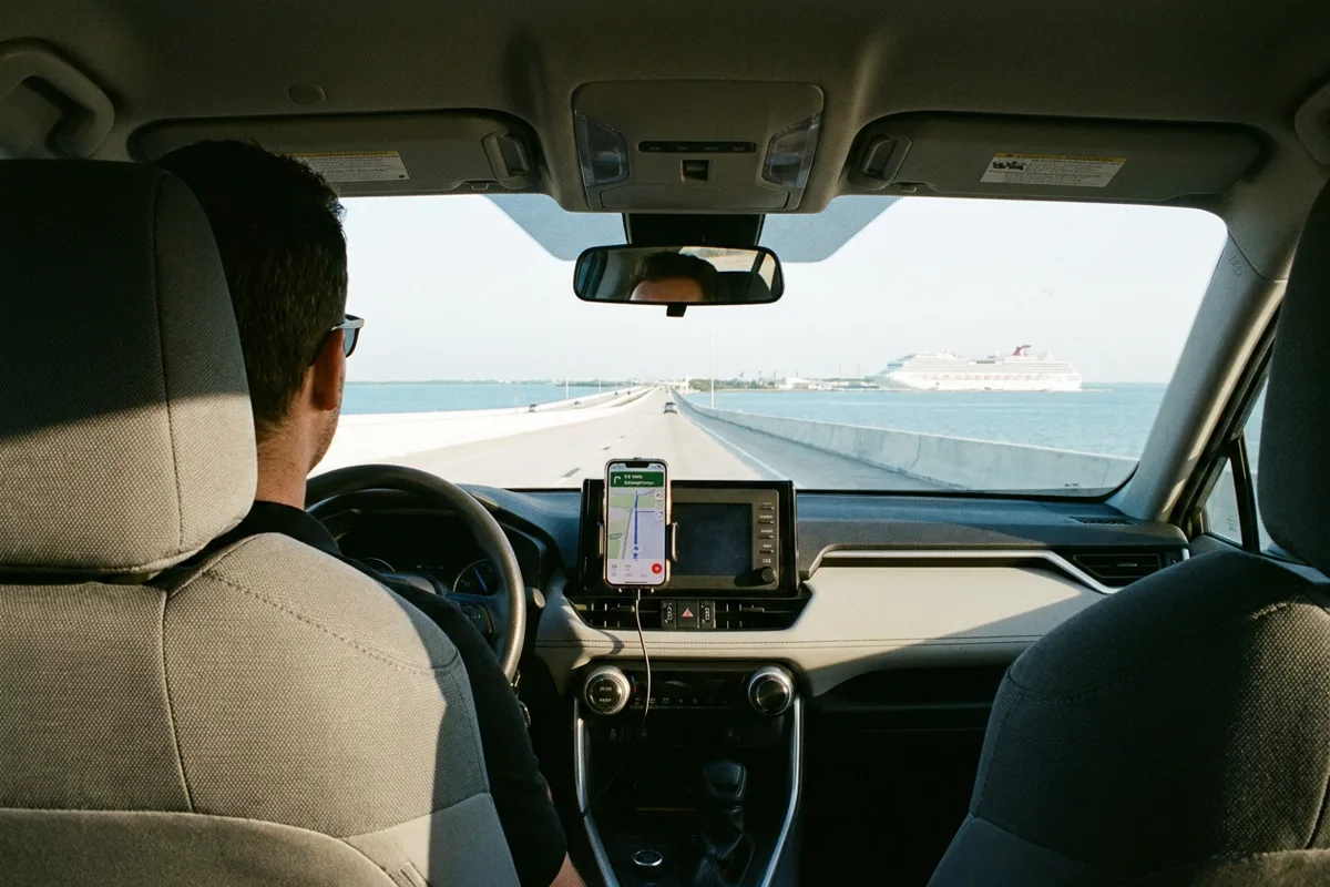View from the back seat of a rideshare SUV crossing the causeway toward Galveston with a cruise ship visible on the horizon
